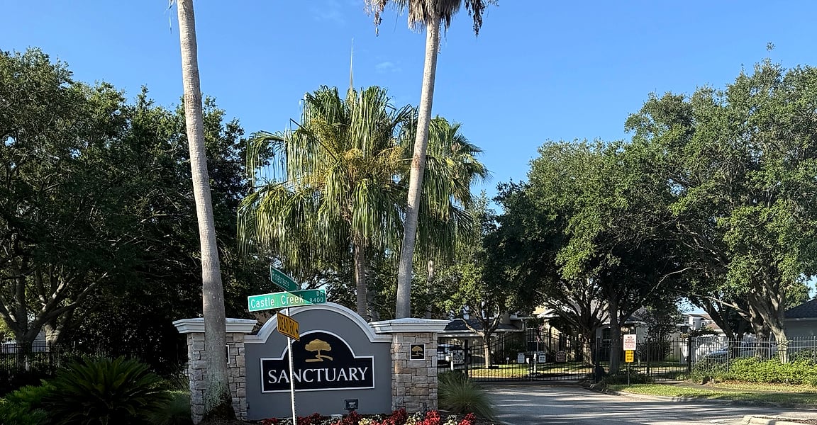 The tree-lined entrance to the Sanctuary at Oak Creek community